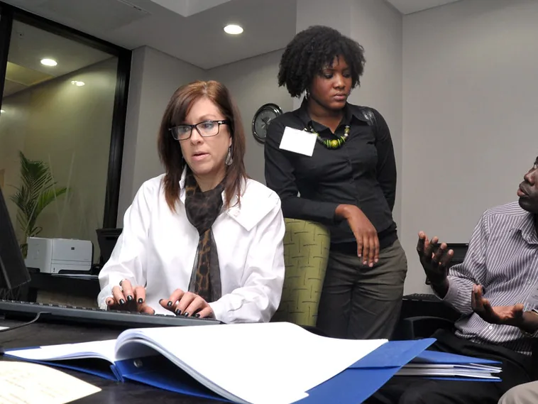 Trois personnes en réunion de travail autour d'un bureau, dans un contexte professionnel africain