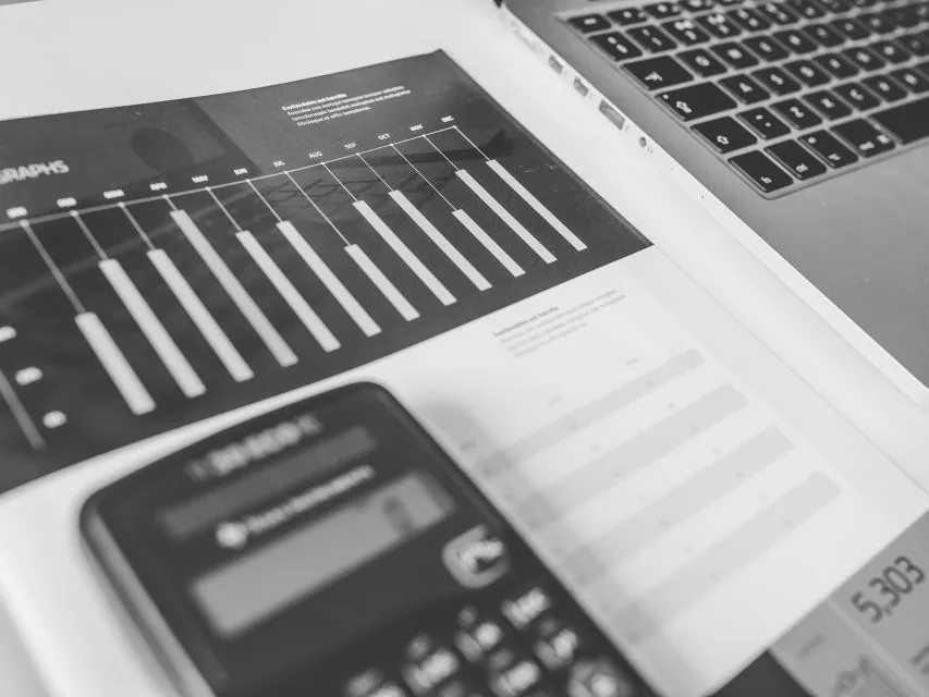 Calculatrice et tableau de chiffres imprimé à côté d'un ordinateur portable — le décompte des frais se fait ligne par ligne