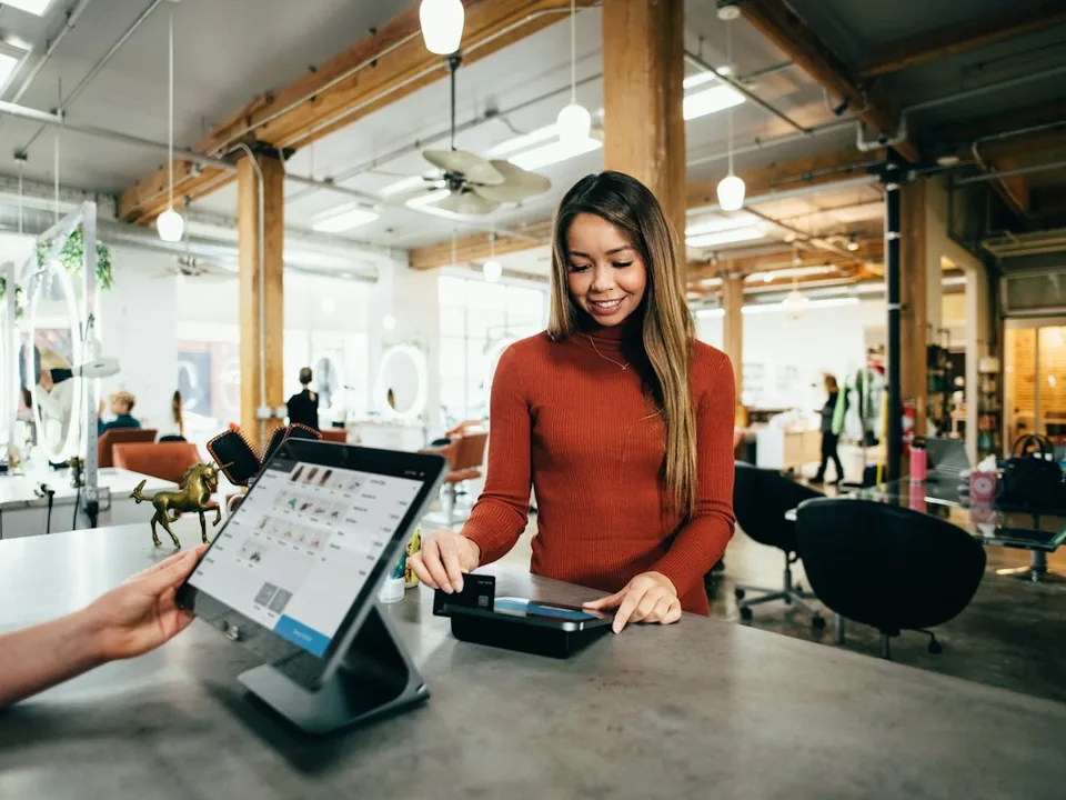 Cliente au comptoir validant un paiement sur un terminal — la remise en FCFA suit la confirmation on-chain